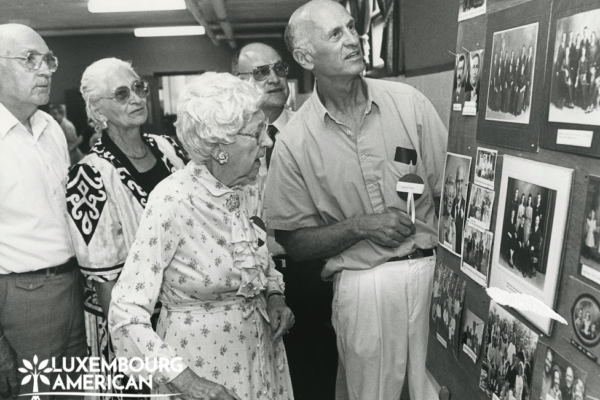Black and white photo of a Group of people looking at a display of photos