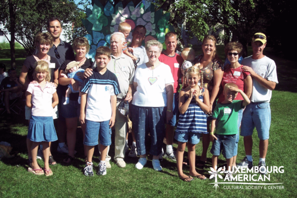 A family posing for a group photo in front of a wooden tree structure