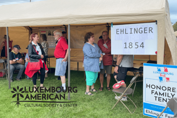 People standing in a tent with a sign that says, "Ehlinger 1854 and Honored family tent"