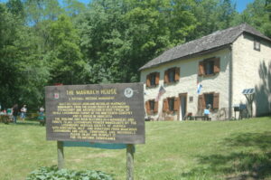 Sign depicting the Marnach House with the Marnach House (stone building with 6 windows and a door on the front)
